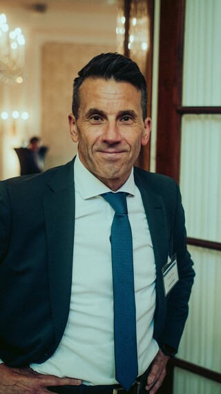 Herr in Anzug hat die Hände in die Hüfte gestemmt.