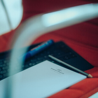 Eine Tastatur und ein Block liegen auf einem roten Sessel.