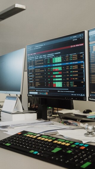 Auf dem Tisch stehen eine Tastatur und mehrere Computer.