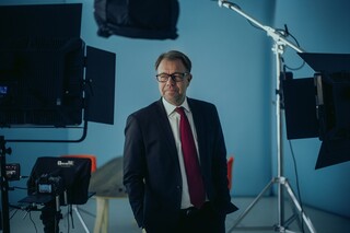 Ein Herr in Anzug steht in einem Fotostudio.