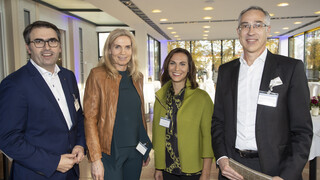 2 Frauen und 2 Männer sind im Bild, alle lächeln freundliche in die Kamera. Sie sind in einem Veranstaltungsraum.