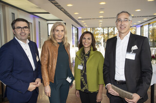 2 Frauen und 2 Männer sind im Bild, alle lächeln freundliche in die Kamera. Sie sind in einem Veranstaltungsraum.