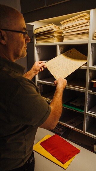 Ein Mann vor einem Regal beim Einräumen in ein Fach.