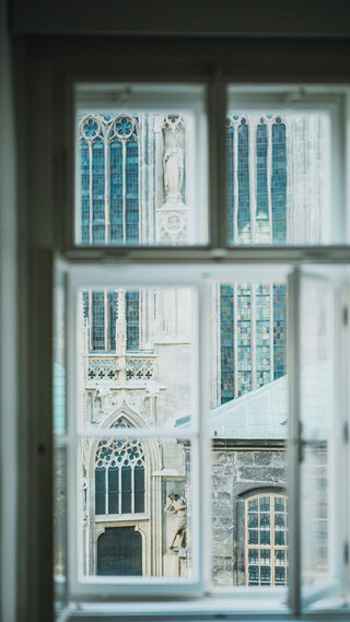 Blick durch ein Sprossenfenster auf einen Sakralbau.
