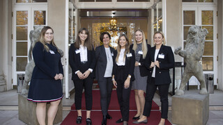 Sechs Frauen (alle schwarz-weiß gekleidet) stehen im äußeren Eingangsbereich eines historischen Gebäudes (Kavalierhaus Klessheim, Salzburg). Alle Lächeln freundlich.