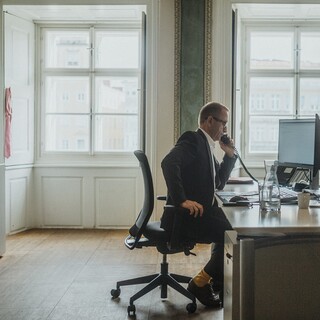 Ein Herr in Anzug telefoniert an einem Schreibtisch in einem historischen Büro.