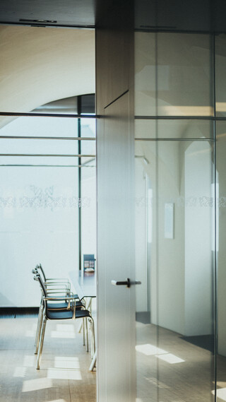 In einem modernen Raum mit vielen Glaselementen steht in Tisch mit Sesseln.