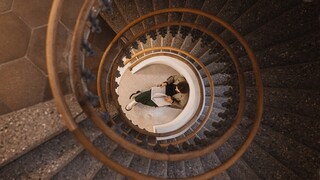 n der Mitte einer runden Steintreppe sitzt eine Frau und liest Zeitung.