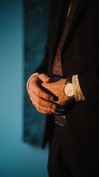 Verschränkte Hände eines Herren, welche von vorne mit warmen Licht angeleuchtet werden.