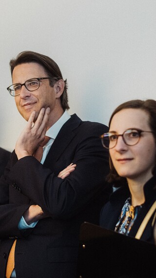 Personen in Geschäftskleidung blicken gespannt in eine Richtung.