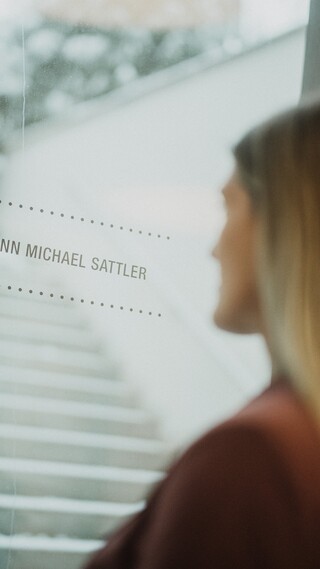 Eine blonde Frau schaut aus dem Fenster. 