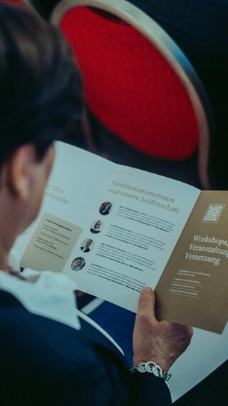 Blick über die Schulter einer Dame, welche einen ausgefalteten Flyer liest.