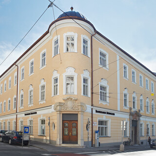 Außenansicht eines hellgelb gefärbten historischen Gebäudes unter blauem Himmel.