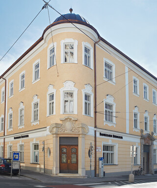 Außenansicht eines hellgelb gefärbten historischen Gebäudes unter blauem Himmel.