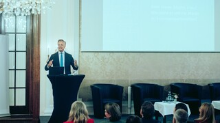 Dr. Werner Zenz hält eine Rede vor dem Publikum im Rahmen des Forums Familienunternehmen 2024. In der linken oberen Ecke ist ein Kronleuchter zu sehen, im rechten Teil des Bildes eine Leinwand. 