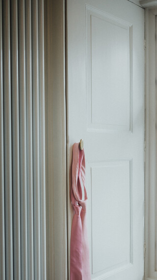 Zwei rosa Krawatten hängen auf einem weißen Fensterladen.