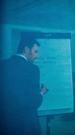 Ein Herr in Geschäftskleidung beschreibt ein Flipchart.