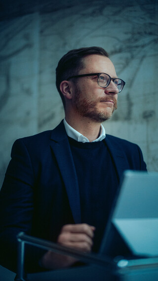 Ein Herr in Geschäftskleidung sitzt vor einem Tablett.