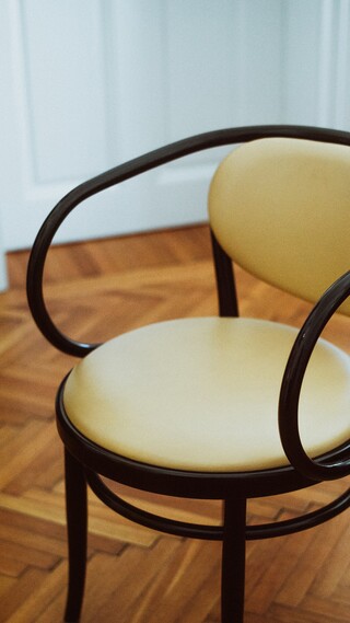 Ein Sessel steht auf einem Parkettboden.