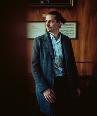 In einem dunklen Raum sitzt ein Mann und schaut nach rechts.