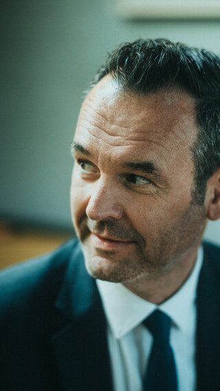 Ein Herr in Geschäftskleidung blickt zur Seite.