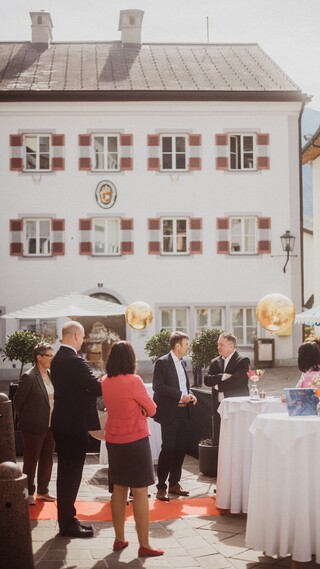 Festlich gekleidete Personen und dekorierte Stehtische auf einem Stadtplatz.