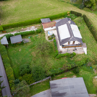 Älteres Einfamilienhaus mit Garten in grüner Landschaft aus der Vogelperspektive.