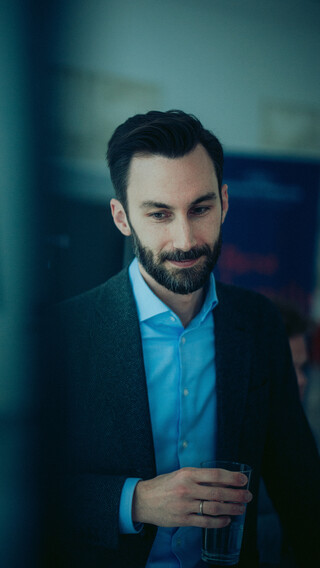 Ein Herr in Geschäftskleidung steht in einem modernen Raum.