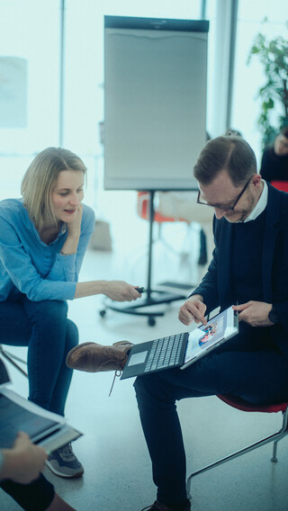 Eine Dame und ein Herr blicken auf ein Tablet.