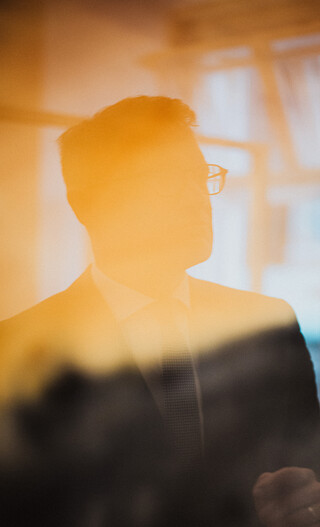 Ein Herr in Geschäftskleidung spiegelt sich in einem Gemälde.