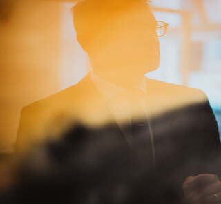 Ein Herr in Geschäftskleidung spiegelt sich in einem Gemälde.