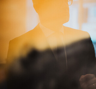 Ein Herr in Geschäftskleidung spiegelt sich in einem Gemälde.