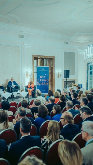 Publikum lauscht einer Podiumsdiskussion in einem historischen Saal.