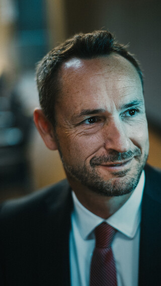 Ein Herr in Geschäftskleidung blickt in die Ferne.